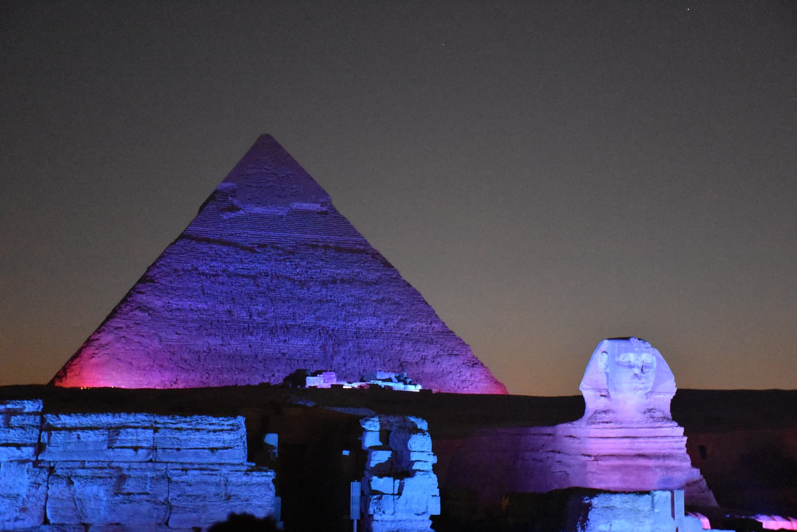 A pyramid and the Sphinx lit in purple and blue during the evening show
